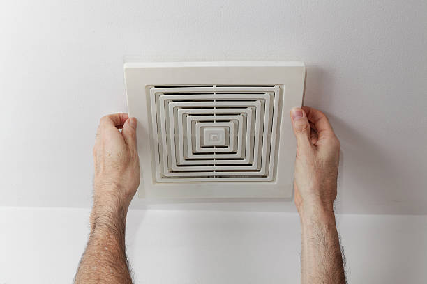 man's hands removing air duct cover from ceiling